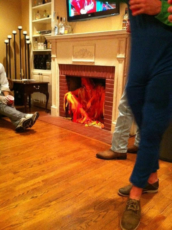 Man dressed as a fire sitting in a fireplace