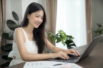 Asian girl typing data to her computer notebook for prepare her report